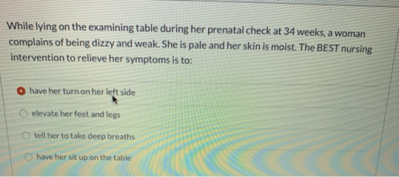 While lying on the examining table during her prenatal check at 34 weeks, a woman complains of being dizzy and weak. She is p